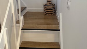 A staircase with wooden steps and white railings, leading to a landing with a decorative woven structure. - The little cocoon (Vierzon)