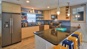 A modern kitchen with a central island, built-in appliances, and bar stools. - FLIP FLOP LIING 2! 4 Bdrms, 3 Bths, STEPS TO THE SAND! (New Smyrna Beach)
