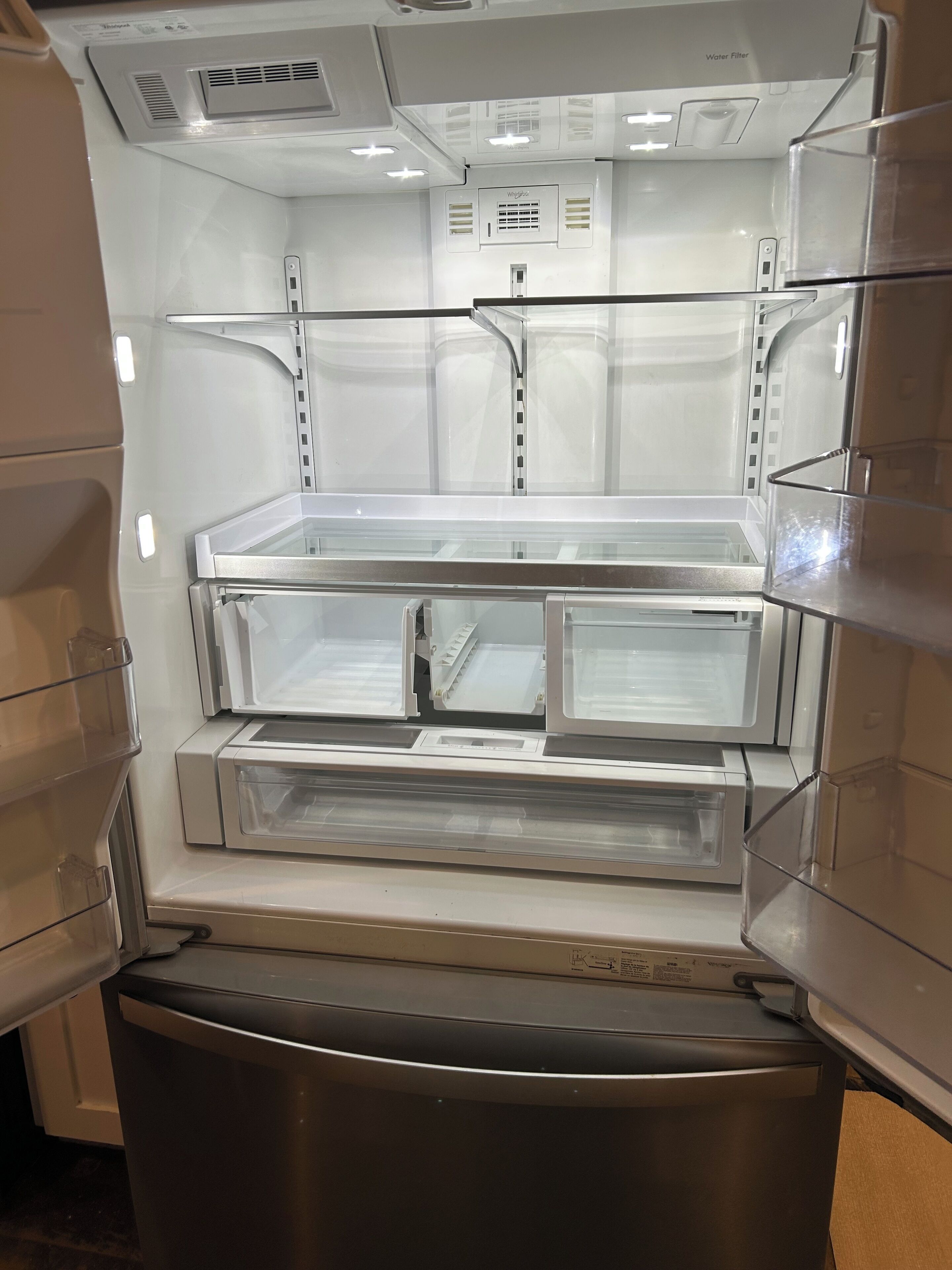 A stainless steel refrigerator with two shelves and a water filter compartment.