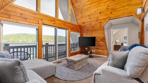 Un salón acogedor con televisor grande, asientos cómodos y vistas al exterior.