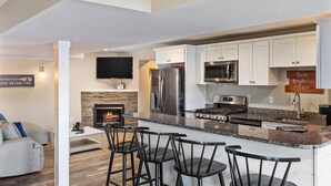 Una cocina moderna con armarios blancos, horno empotrado y una isla grande con taburetes de bar.