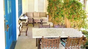 An outdoor patio with a table and chairs, a sofa, and a blue door.