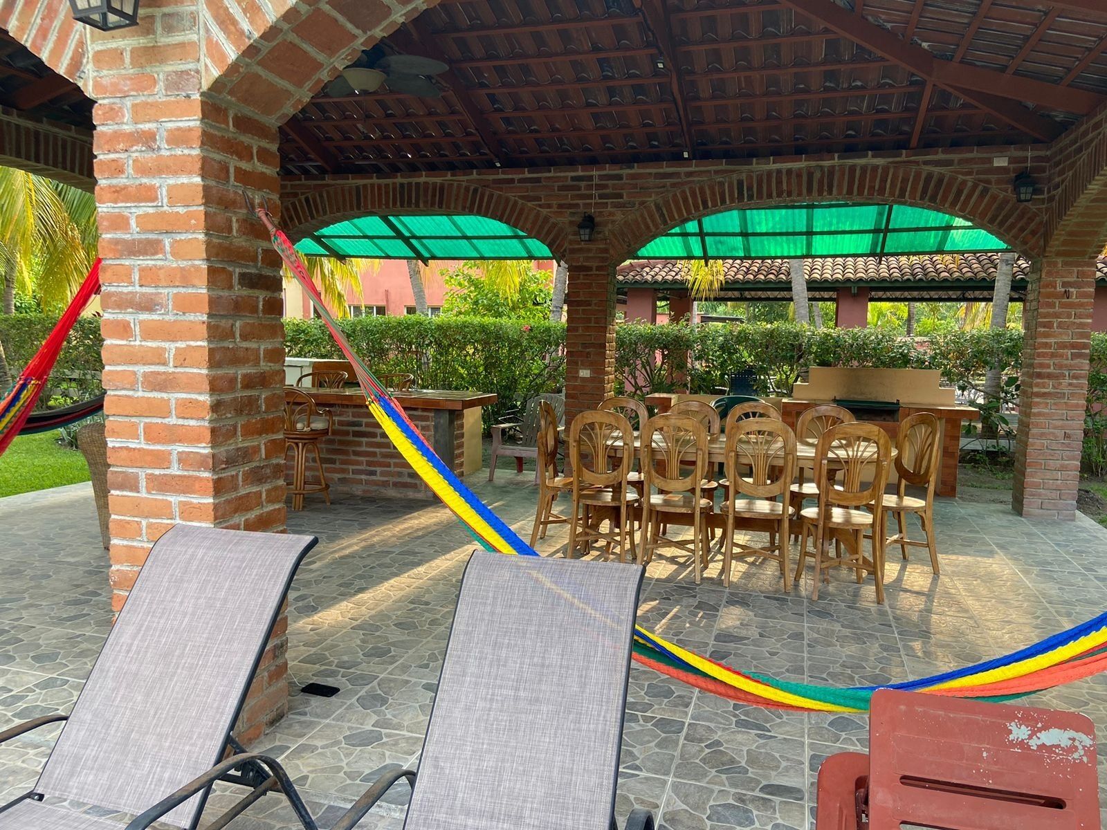 A covered outdoor seating area with brick pillars, a table, and chairs.