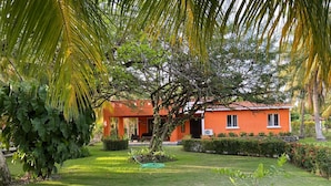 A house with a red exterior, surrounded by a well-maintained garden with various plants and a lawn.