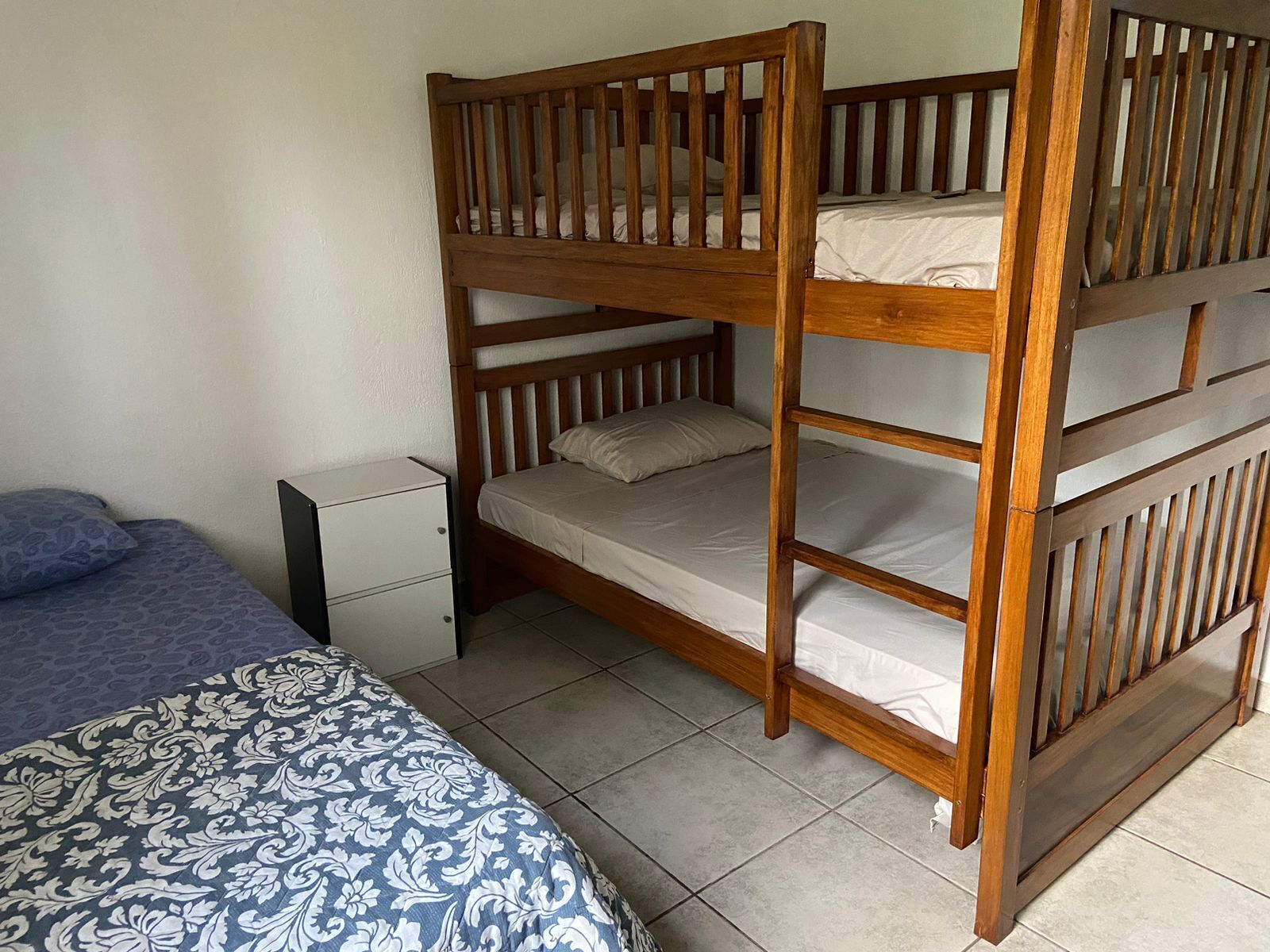 A bunk bed with a lower bunk and a single bed with a patterned bedspread.