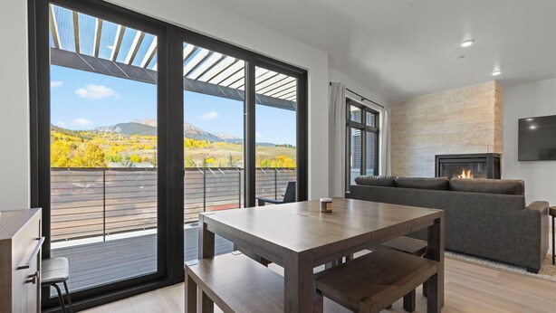 Een moderne woonkamer met een open haard, een eettafel en een bank.