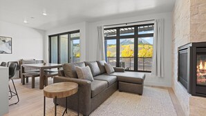 Een moderne woonkamer met een modulaire bank, een eettafel en een open haard.
