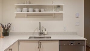 Una cocina moderna con armarios blancos, lavavajillas de acero inoxidable y un lavamanos integrado.