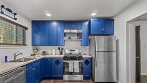 Una cocina con armarios azules, un refrigerador de acero inoxidable, una estufa y un microondas.