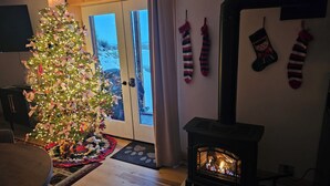 Una sala de estar con un árbol de Navidad decorado, una chimenea y calcetines navideños en la pared.