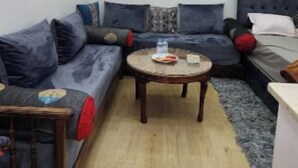 En moderne stue med en hjørnesofa, et rundt sofabord og en loftlampe.