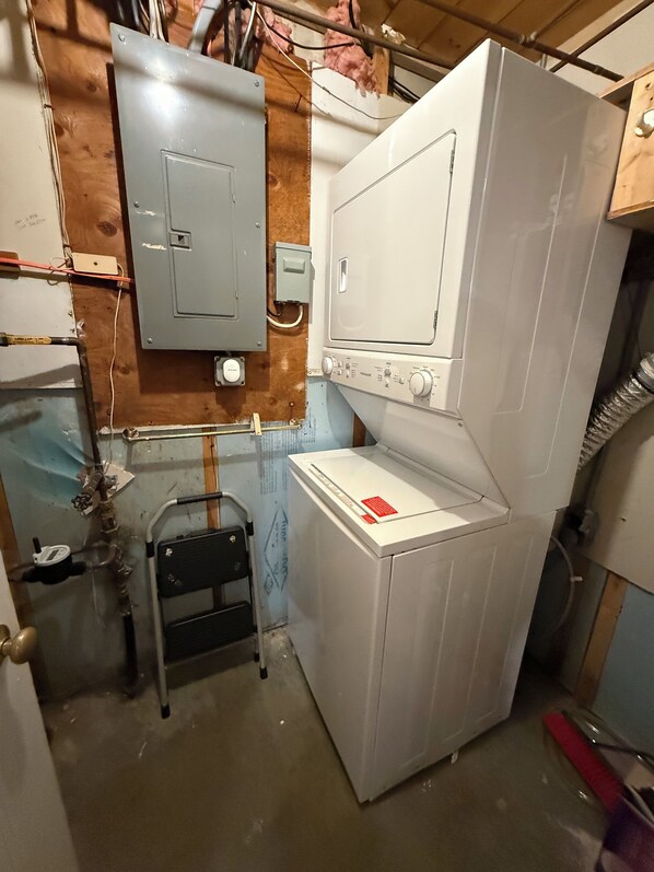 Une petite buanderie équipée d’un lave-linge, d’un sèche-linge et d’un tableau électrique.