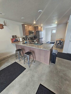A kitchen with a central island, stainless steel appliances, and a dining area with a table and chairs. - Cozy 2BR Home Parking and Full Kitchen (Stanfield)