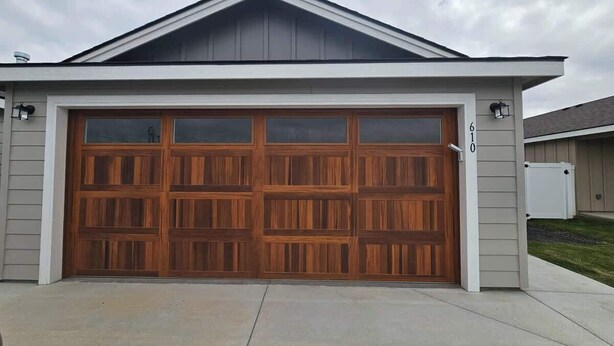 A residential garage with a large wooden door, a sloped roof, and a number '610' on the wall. - Cozy 2BR Home Parking and Full Kitchen (Stanfield)