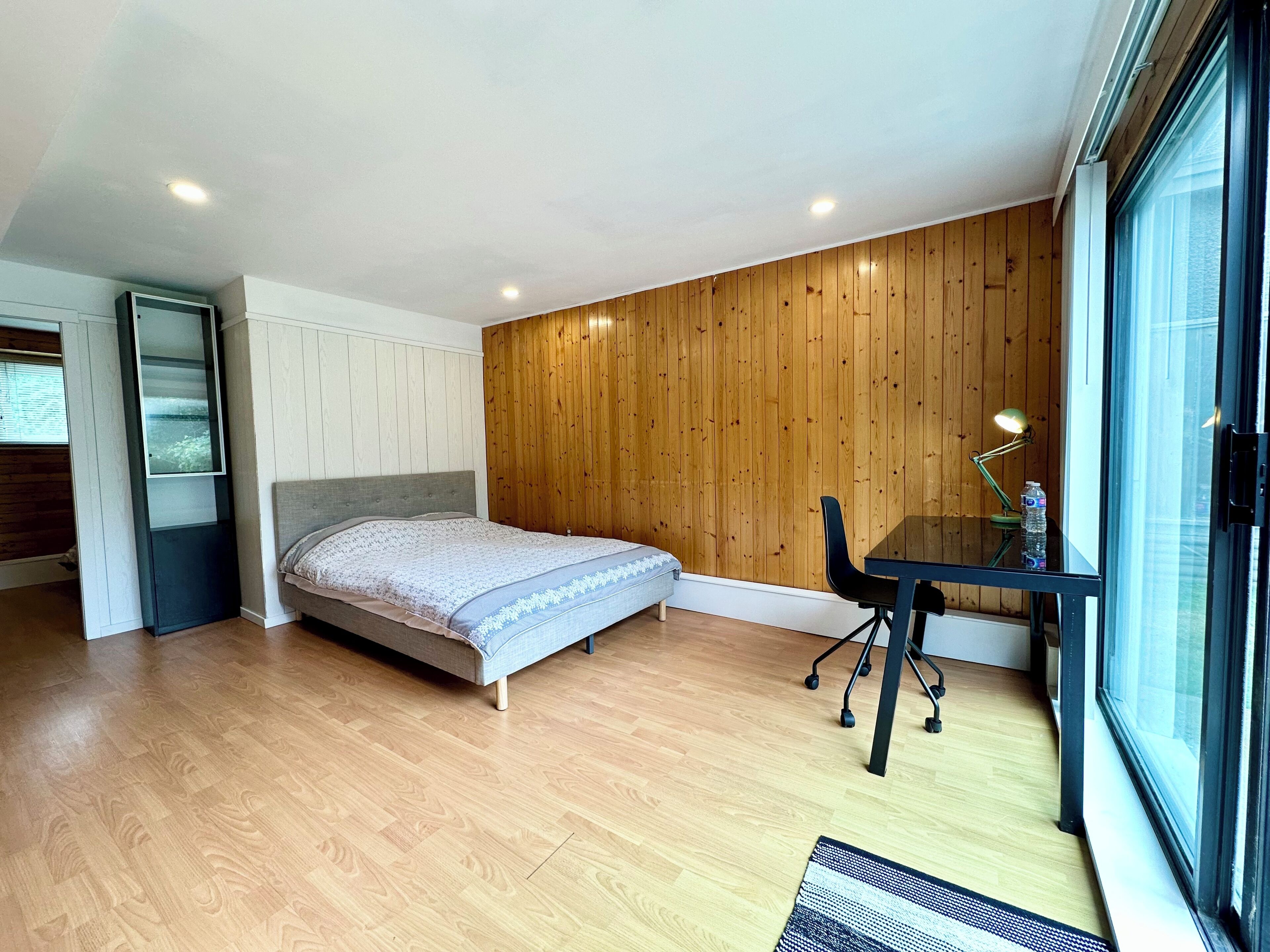 A bedroom with a bed, a desk, and a chair.