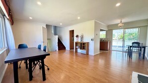 Uma sala ampla com mesa de jantar, cadeiras, escada e área de cozinha.