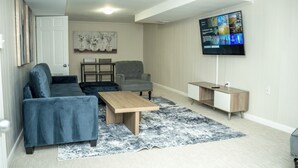 Moderni olohuone, jossa on sohva, nojatuoli, sohvapöytä ja televisio.