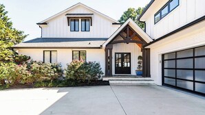 A two-story house with a garage, a covered front porch, and a well-maintained garden. - Lakefront Home with Pool and Hot tub (Cornelius)