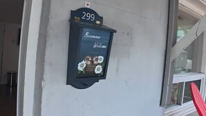 Husnummer 299, en postkasse med et 'Velkommen'-skilt og et lille vindue.