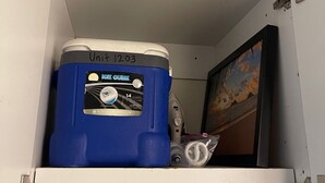 Un compartimento de almacenamiento con un contenedor azul etiquetado 