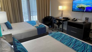 Habitación de hotel con dos camas, un escritorio, una silla, un televisor y una lámpara de escritorio.