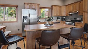 A modern kitchen with wooden cabinets, stainless steel appliances, and a central island with bar stools. - Luxury Evergreen Retreat · Fireplace · Mountain Views · 45 min Denver  (Evergreen)