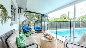 A covered outdoor area with a pool, two hanging chairs, and a wicker table. - 3 BDRM Florida Charmer in Venice FL- Private Pool+King Bed+Parking for Boats/RVs (Venice)
