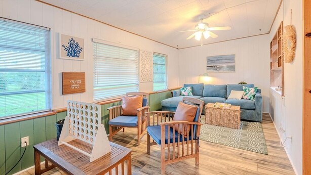 A cozy living room with a blue sofa, wooden chairs, a wooden coffee table, and a ceiling fan. - 3 BDRM Florida Charmer in Venice FL- Private Pool+King Bed+Parking for Boats/RVs (Venice)