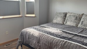 Une chambre à coucher avec un lit, deux fenêtres et un tapis à motifs.