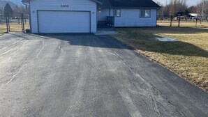 Une maison à deux étages avec un garage, un petit porche et une allée menant au garage.