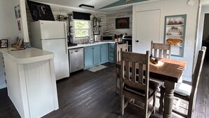 Une cuisine compacte avec un coin repas, comprenant un réfrigérateur, un four à micro-ondes, un évier et des chaises en bois.