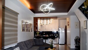 A modern living room with a grey sectional sofa, a coffee table with a vase, and a kitchen area in the background.