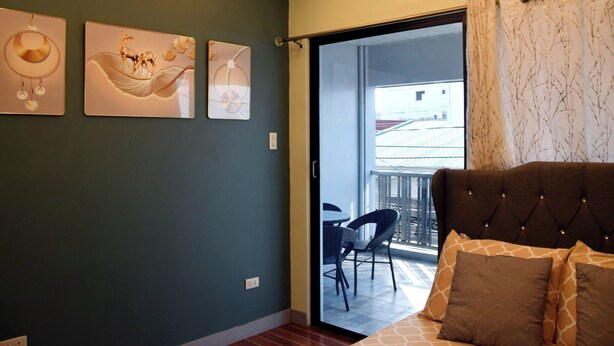 A bedroom with a bed, a balcony with chairs, and artwork on the wall.
