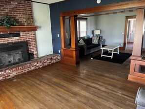 A living room with a brick fireplace, wooden flooring, a sofa, and a coffee table.