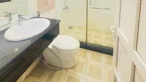 Ein modernes Badezimmer mit einer Duschkabine, einer weißen Toilette und einem großen Spiegel.