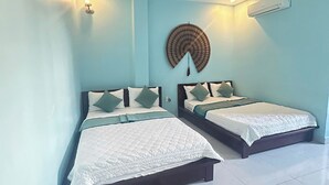 Ein Hotelzimmer mit zwei Betten, einer Wand-Klimaanlage und einem Deckenventilator.