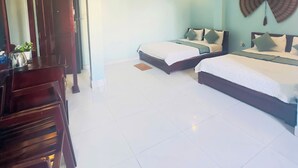Ein Hotelzimmer mit zwei Betten, einem Schreibtisch, einem Stuhl, einem Ventilator und einem Wandventilator.