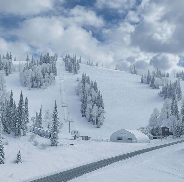 Un paisaje nevado con una carretera, un edificio pequeño y una gran estructura en forma de cúpula.
