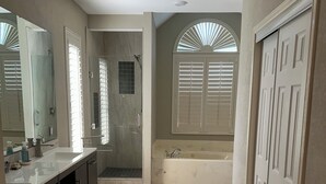 Un baño con bañera, ducha, tocador con espejo y perchero.