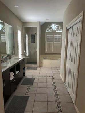 Un bagno con vasca, doccia, lavabo con specchio e porta asciugamani.