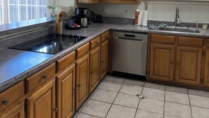 Una cocina con armarios de madera, un lavamanos de acero inoxidable y un lavavajillas.