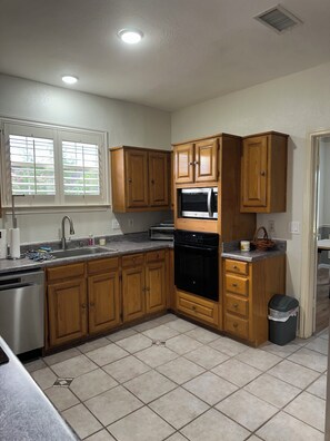 A kitchen with wooden cabinets, a stainless steel sink, a microwave, and a dishwasher.