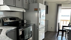 A kitchen with grey cabinets, a stainless steel oven, a white refrigerator, and a granite countertop.