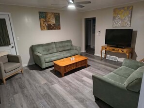 A living room with a sofa, a coffee table, a television, and artwork on the walls.