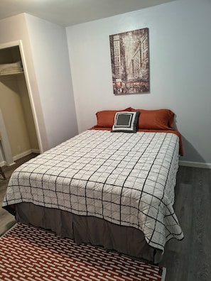 A bedroom with a bed, a painting on the wall, and a closet.