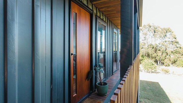 A modern building with a wooden door and a potted plant on the porch. - Cosy container house walking distance to town. (Korumburra)