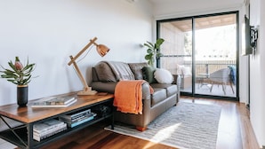 A modern living room with a sofa, a coffee table, and a bookshelf. - Cosy container house walking distance to town. (Korumburra)