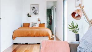 A bedroom with a bed, a desk, a chair, a lamp, and a plant. - Cosy container house walking distance to town. (Korumburra)