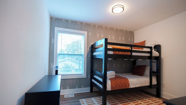 A bunk bed room with a window, a desk, and a patterned rug. - Luxury 4BR 4BA • In-law suite • Firepit Lounge (Decatur)