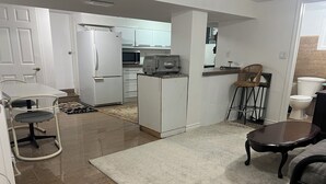 Un espacio habitable compacto con kitchenette, un comedor con mesa y sillas, y una pequeña sala de estar con sofá y mesa de centro.